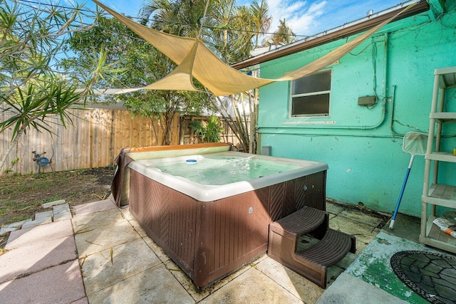 view of patio featuring cooling unit, fence, and a hot tub