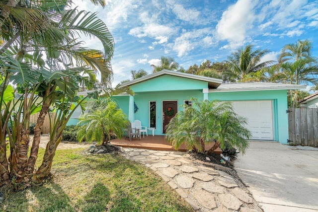 view of front facade featuring stucco siding, driveway, a garage, and fence