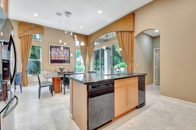 kitchen featuring an island with sink, stainless steel fridge, sink, decorative light fixtures, and dishwasher