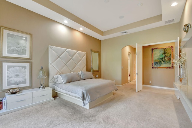 bedroom featuring a tray ceiling and light colored carpet