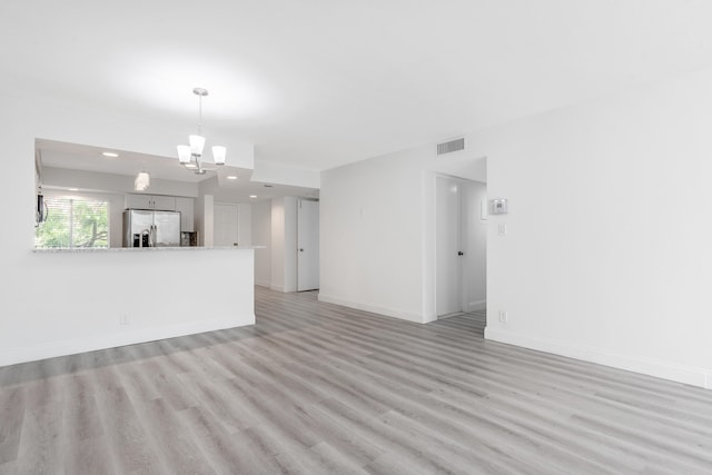 unfurnished living room with light hardwood / wood-style flooring and a notable chandelier