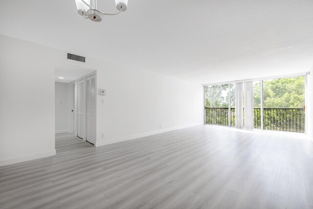 spare room with light hardwood / wood-style flooring and a notable chandelier