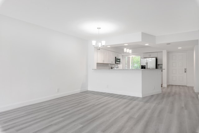 unfurnished living room with a notable chandelier and light hardwood / wood-style floors