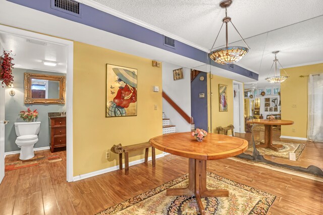 dining room featuring hardwood / wood-style floors, a textured ceiling, and crown molding