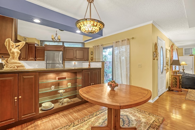 dining space with ornamental molding, sink, a textured ceiling, and light hardwood / wood-style floors