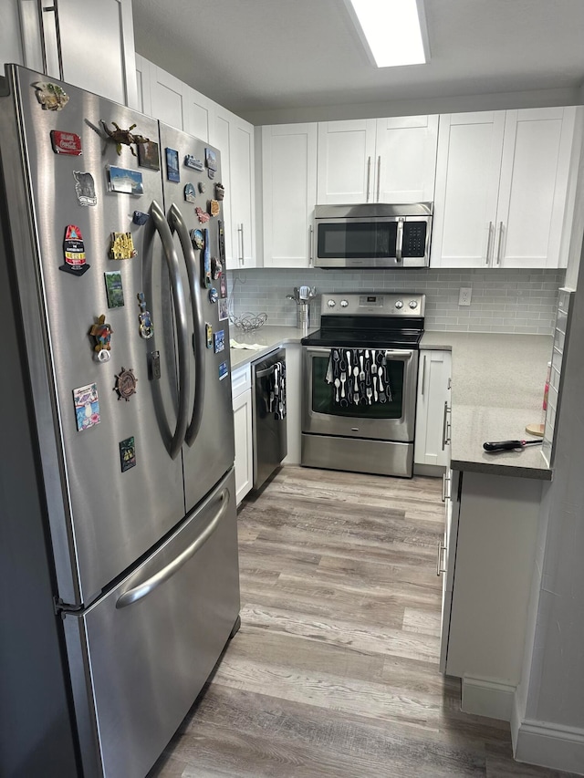 kitchen featuring appliances with stainless steel finishes, white cabinetry, backsplash, and light hardwood / wood-style floors