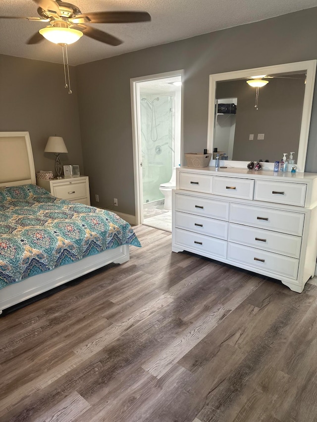 bedroom featuring dark hardwood / wood-style flooring, ceiling fan, connected bathroom, and a textured ceiling