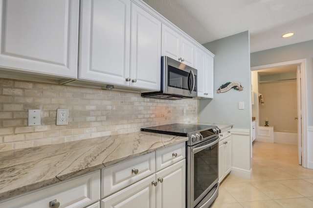 kitchen featuring light stone counters, light tile patterned flooring, white cabinets, decorative backsplash, and stainless steel appliances