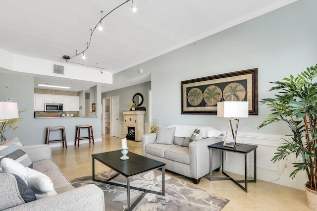 living room featuring ornamental molding, a fireplace, light tile patterned flooring, and rail lighting