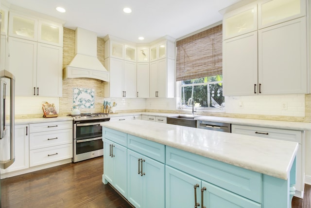 kitchen with premium range hood, sink, a center island, stainless steel appliances, and blue cabinetry