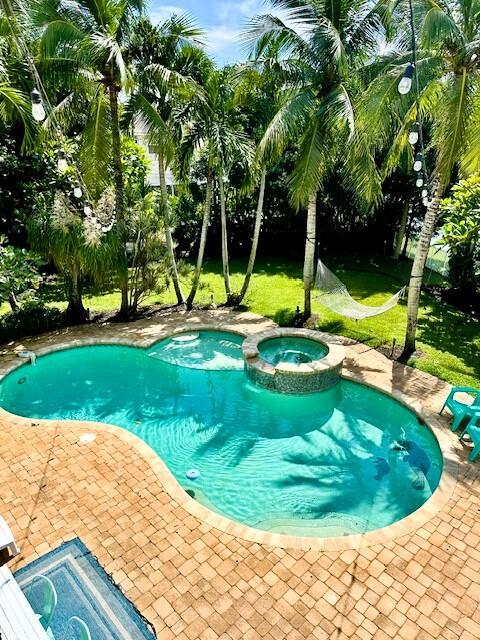 view of swimming pool with a yard, a patio, and an in ground hot tub