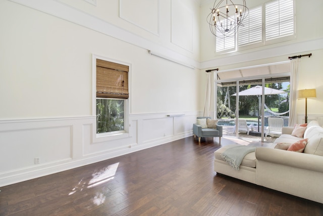 living room featuring a high ceiling, dark hardwood / wood-style floors, and a chandelier