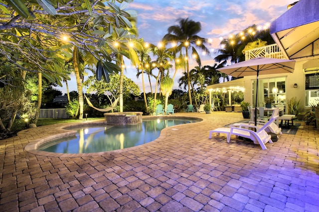 pool at dusk featuring a patio area