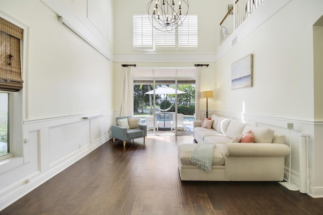 living room with dark hardwood / wood-style flooring, a towering ceiling, and a chandelier