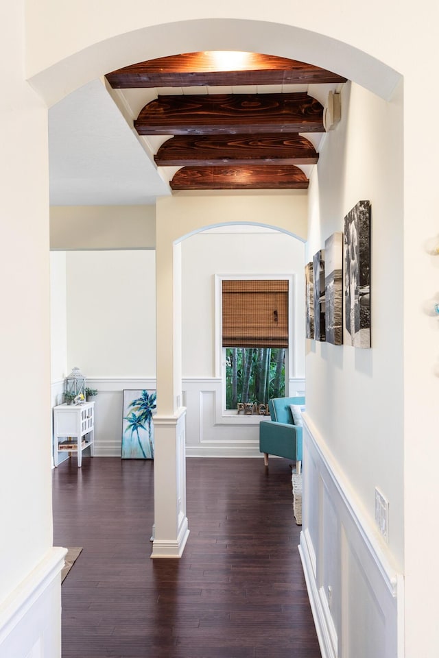 corridor with decorative columns, dark hardwood / wood-style floors, and beamed ceiling