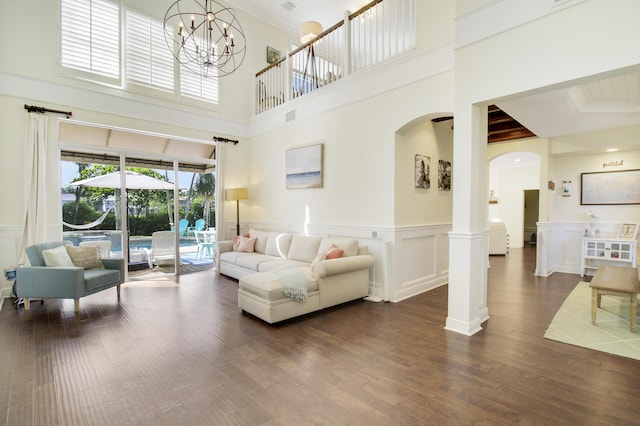 living room with ornate columns, dark wood-type flooring, and a chandelier