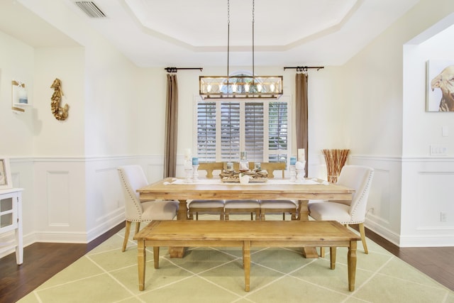 dining room featuring a raised ceiling, dark wood-type flooring, and a notable chandelier