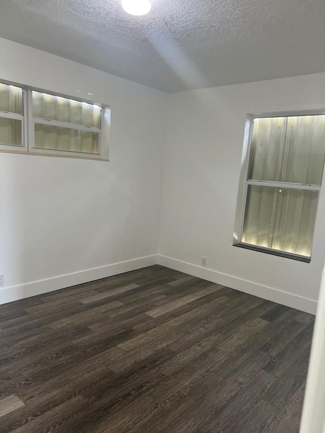 unfurnished room with a textured ceiling and dark hardwood / wood-style floors