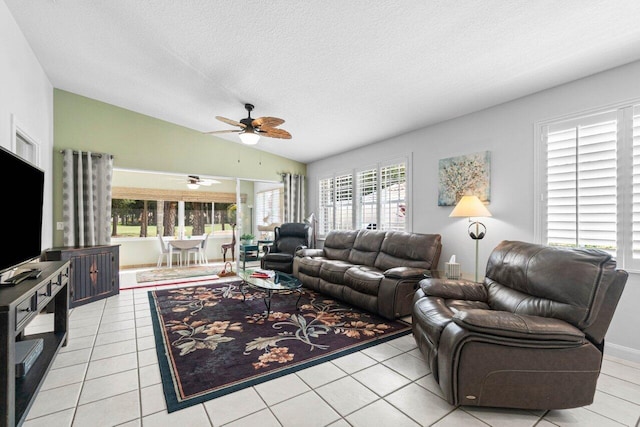 tiled living room featuring a textured ceiling, lofted ceiling, ceiling fan, and plenty of natural light