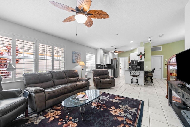 living room with a textured ceiling, light tile patterned flooring, ceiling fan, and a wealth of natural light