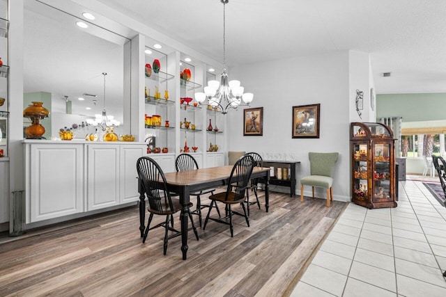 dining space featuring an inviting chandelier, light wood-type flooring, vaulted ceiling, and a textured ceiling