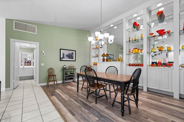 dining space with an inviting chandelier, vaulted ceiling, and hardwood / wood-style flooring