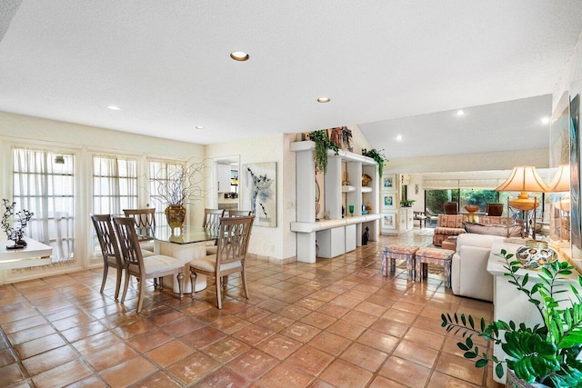 dining room with light tile patterned flooring, lofted ceiling, a textured ceiling, and a wealth of natural light