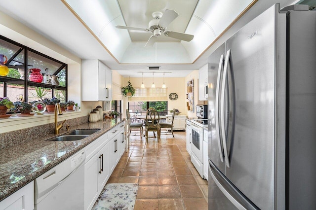 kitchen with white appliances, a raised ceiling, sink, white cabinets, and hanging light fixtures