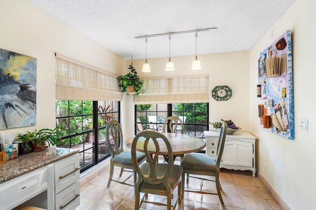 dining area featuring rail lighting and a textured ceiling