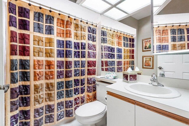 bathroom featuring a shower with shower curtain, vanity, and toilet