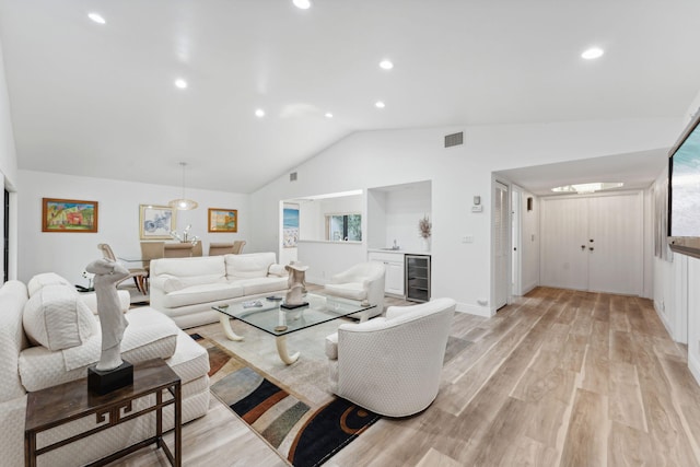 living room with beverage cooler, vaulted ceiling, light hardwood / wood-style floors, and plenty of natural light