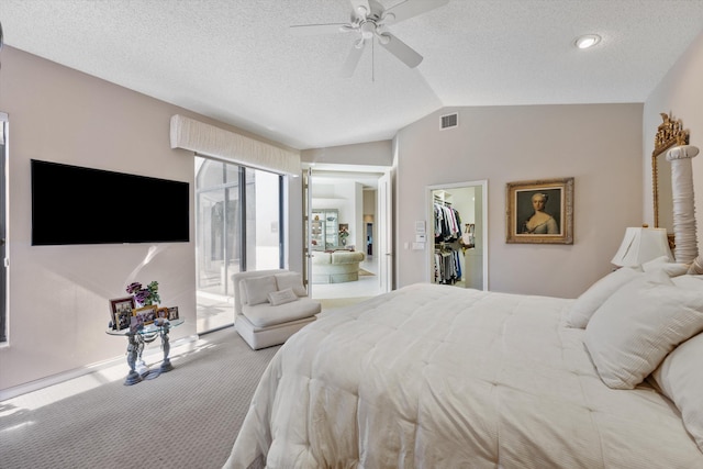 bedroom with lofted ceiling, ceiling fan, connected bathroom, a walk in closet, and carpet