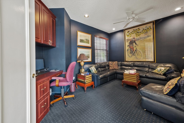 carpeted office with ceiling fan, built in desk, and a textured ceiling