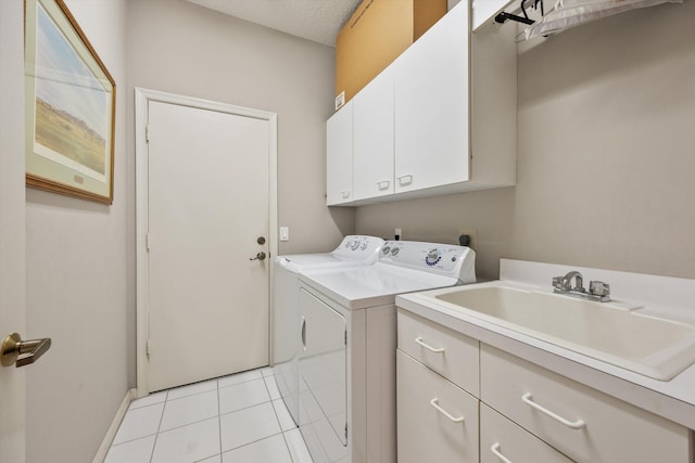 laundry area with cabinets, sink, washing machine and dryer, light tile patterned floors, and a textured ceiling