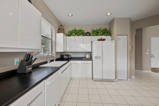 kitchen with white appliances, white cabinetry, sink, light tile patterned floors, and a textured ceiling