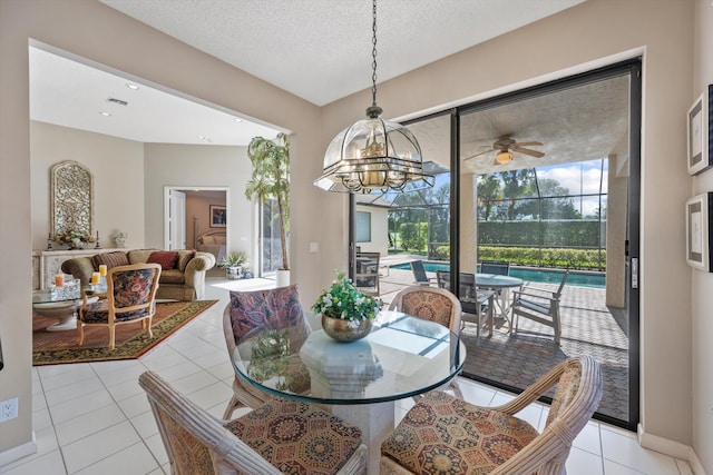 tiled dining area with ceiling fan with notable chandelier and a textured ceiling