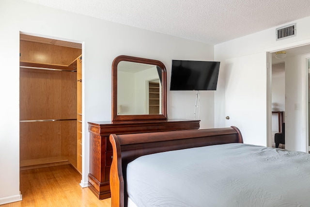 unfurnished bedroom with light wood-type flooring, a closet, and a textured ceiling