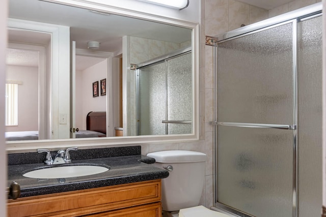 bathroom with vanity, a shower with shower door, and toilet