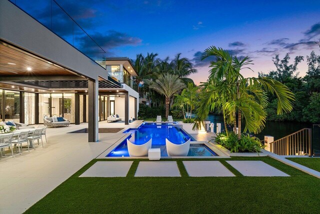 pool at dusk with a patio and a yard