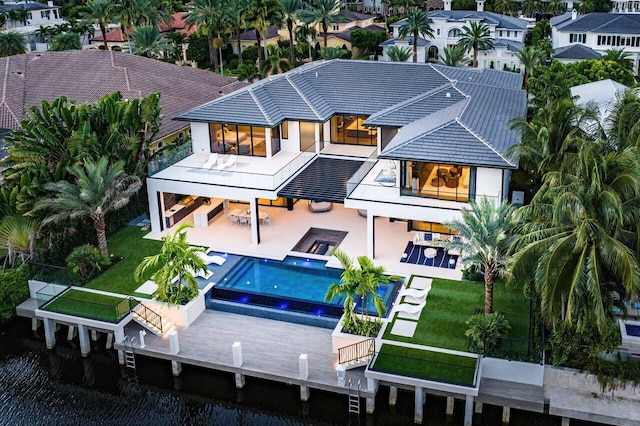 rear view of property featuring a lawn, a patio, an outdoor living space, and a pool with hot tub