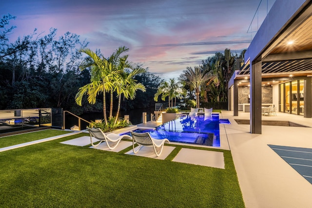 pool at dusk featuring a yard and a patio