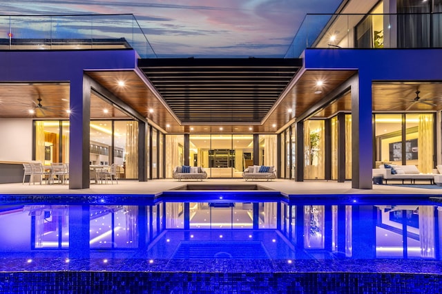 pool at dusk featuring ceiling fan