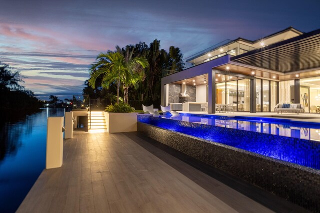 pool at dusk with exterior kitchen