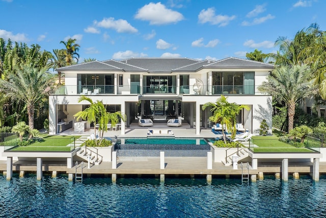 rear view of house with a balcony, a water view, an outdoor hangout area, and a patio area