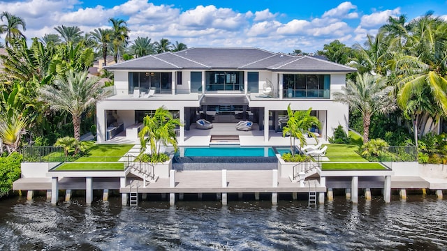 back of house with a balcony, a lawn, a water view, and a patio area