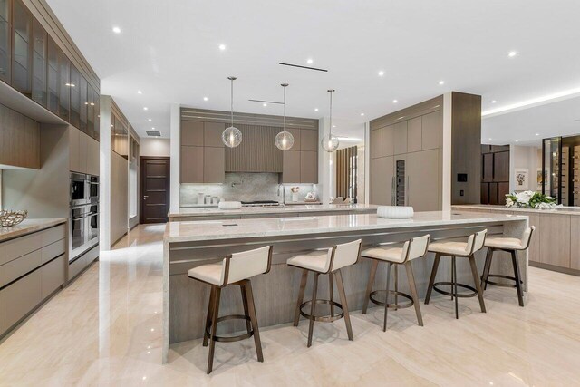 kitchen featuring a spacious island, backsplash, light stone counters, and a breakfast bar