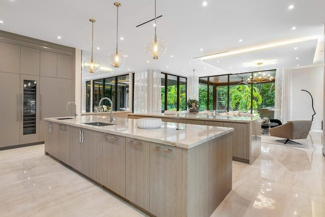 kitchen featuring light stone countertops, hanging light fixtures, a spacious island, and sink