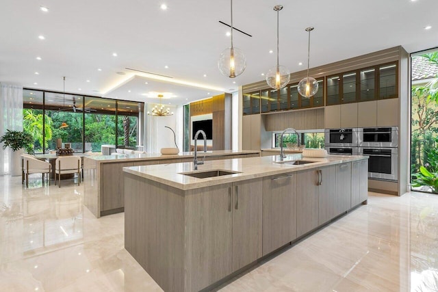 kitchen with decorative light fixtures, double oven, a large island with sink, and sink