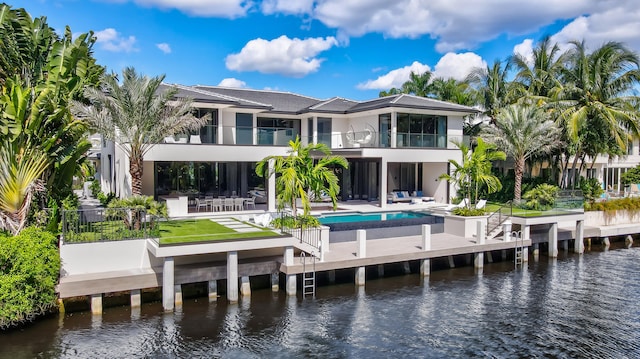 rear view of house with a patio, a water view, and a balcony