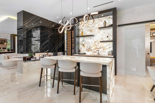 kitchen featuring pendant lighting, a large fireplace, light stone countertops, and a breakfast bar area